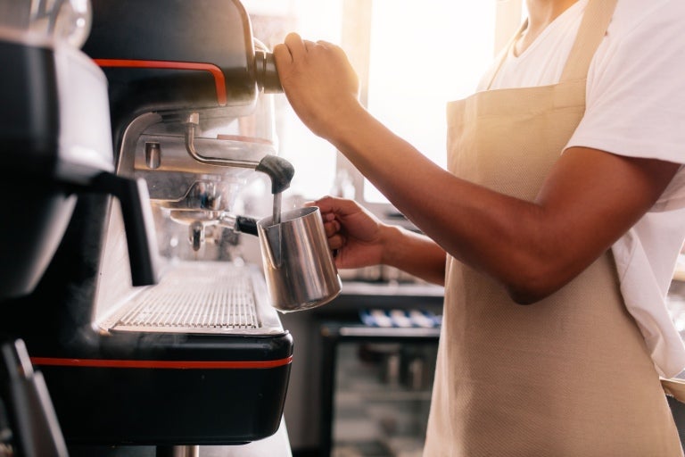 baristka spieniająca mleko przy ekspresie